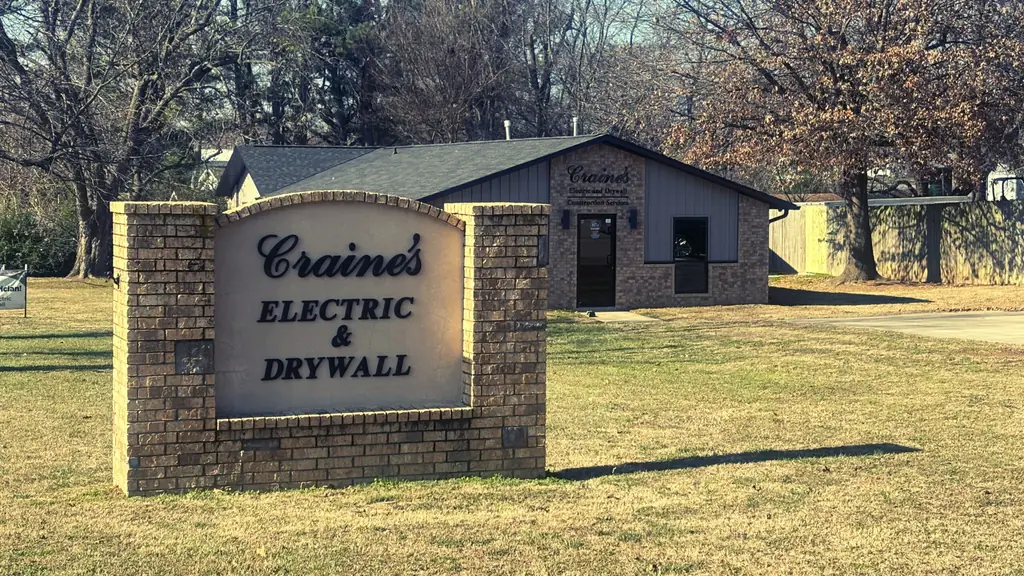 The brick Craine's Electric & Drywall sign in front of the home office on Elm Springs Road